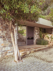 Poster - A modern design house stone paved entrance with a glass door and a view to the garden. Visit upscale neighborhoods of Athens, Greece.