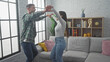 © Krakenimages.com - A man and woman dance joyfully in a stylish living room, expressing love and togetherness in a cozy home setting.