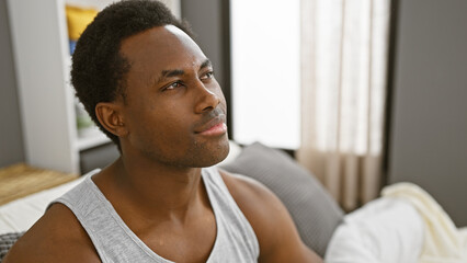 Wall Mural - Portrait of a thoughtful young man sitting in a modern bedroom with natural light streaming in.