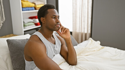 Wall Mural - Thoughtful african american man in bedroom looking contemplative at home