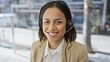 © Krakenimages.com - Smiling young hispanic woman wearing a headset in a professional setting with a blurred background.