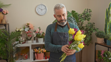 Wall Mural - Handsome man arranging colorful flowers in a cozy indoor florist shop