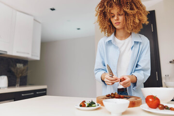 Wall Mural - A woman with curly hair standing in the kitchen preparing a plate of food on the counter