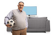 © Ljupco Smokovski - Happy elderly man holding a football in front of tv and smiling