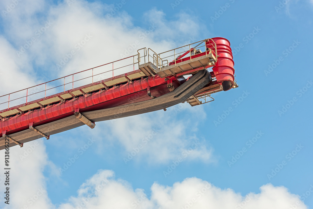 industrial red treadmill stands out against a cloudy blue sky