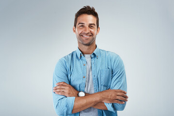 Wall Mural - Arms crossed, fashion and smile with portrait of man in studio on gray background for casual style. Confident, denim and shirt with happy model in clothes outfit for chilling, comfort or relax