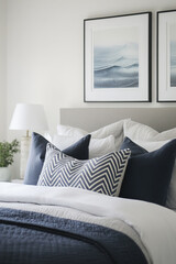 Wall Mural - A close-up shot of the bed, showcasing navy blue and grey bedding with chevron pattern pillows against a plain white wall adorned with framed art. The room exudes an air of tranquility with soft light