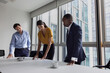 © ReeldealHD images - Team of business executives standing in a meeting room looking at ideas