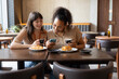 © ReeldealHD images - Female friends looking at phones together in a cafe