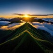 © pimnada - Breathtaking sunrise over mountain peaks, with lush greenery and soft clouds creating a serene landscape.