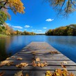 © pimnada - Serene lake view with autumn leaves on a wooden dock under a bright blue sky, capturing nature's tranquil beauty.
