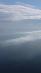 Wall Mural - aerial view. blue sky sun and fog over calm sea. the drone flies over foggy and fluffy clouds. abstr