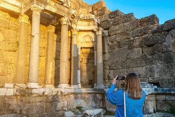 Female tourist takes a photo of the ruins of an ancient city.