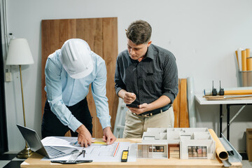 Wall Mural - two colleagues discussing data working and tablet, laptop with architectural project at construction