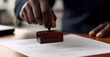 © Mel - Close up of an male hand stamping a document with the word 'APPROVED', lawyer