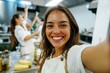 © id512 - joyful young woman taking a selfie during a cooking class in a professional kitchen