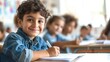 © Andrii  - Happy Schoolboy Writing at Desk in Classroom
