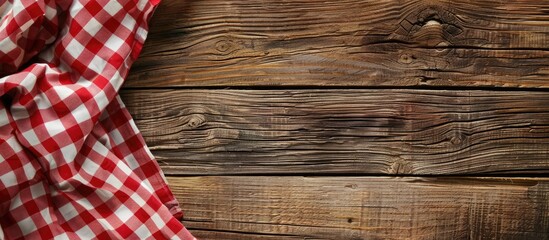 Poster - Red checkered napkin or tablecloth on raw wooden table showing planks and texture with available copy space image