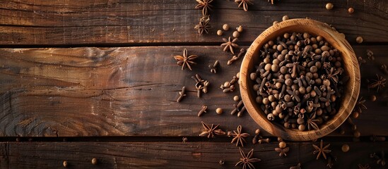 Fototapete - Top view of a wooden table with a bowl of aromatic dry cloves offering a copy space image for text