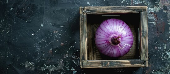 Poster - Top view of a purple onion in a wooden box on a black background with ample space for additional images