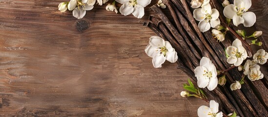 Fototapete - Wooden background with vanilla sticks and flowers for a flat lay composition with room for text in a copy space image