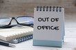 © JeromeMaurice - Out of office text on white notepad with notes and glasses background