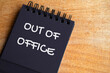 © JeromeMaurice - Top view of Out Of Office text on black notepad. Vacation of annual leave concept
