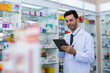 © eakgrungenerd - man pharmacists are selecting medications for patients online via tablet in drug store. Drug seller use tablet check for information before sending to patient.