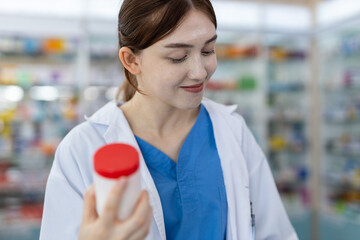 Wall Mural - Drug seller medicine check for information assortment of products in pharmacy. woman pharmacists holding medicine bottle take note record sales on clipboard working at counter drug store.