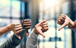 © JordaanExams/peopleimages.com - Business people, thumbs down and no with bad review for negative feedback or disapproval at office. Closeup of group, employees or team with hands for emoji, fail or mistake together at workplace
