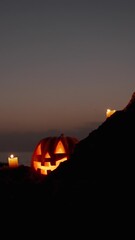 Wall Mural - Vertical video. Jack-O'-Lantern Pumpkin Glows on the Rocks in the Night Sea. Beautiful Sunset Sky on Halloween Night.