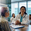 © Miso Ai - A female doctor in a white coat smiles at a patient during a consultation in a hospital setting.