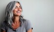 © adobestocker1 - A joyful, smiling woman with gray hair on a light gray background