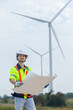 © eakgrungenerd - man engineer worker wearing safety uniform holding and reading blueprint working about renewable energy at station energy power wind. technology protect environment reduce global warming problems.