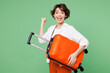 © ViDi Studio - Traveler happy woman wear casual clothes hold orange suitcase bag do winner gesture isolated on plain green background. Tourist travel abroad in free spare time rest getaway. Air flight trip concept.