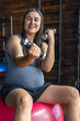 © puhimec - Pregnant woman in the gym sits on a fit ball with dumbbells.