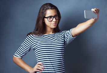 Sticker - Girl, studio and smile with eyeglasses on selfie on grey background for eyesight and eyewear prescription. Woman, satisfied and confident with social media post, profile picture and frame or vision