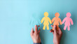 © Oleksiy - Holding paper human figures on light blue background, closeup with space for text. Diversity and inclusion concept