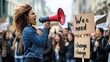 © inthasone - A young African American woman activist on the street shouting a megaphone in a crowd and celebrating human rights with a group of people during a peaceful protest against systematic injustice.