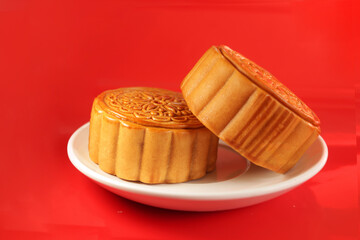 Mooncake on a white plate, tradition chinese mooncake on red background. Mid Autumn celebration, Happy Chinese translation Mid Autumn festival.