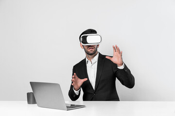 Skilled business man looking at data analysis while sitting at table with laptop and wearing VR glasses. Project manager working by using virtual reality system or connecting at metaverse. Deviation.