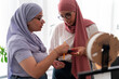 © Studio Marmellata - Two women in hijabs engage in a discussion about 3D printing components. They hold parts and tools, showcasing their involvement in the technical aspects of the project.