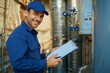 © NN AI - Smiling technician in uniform and cap servicing home water heater, holding clipboard and pen, demonstrating professionalism, doing maintenance. The technician supports the operation of home appliances