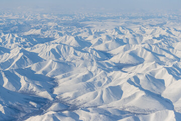 Wall Mural - aerial view of snow-capped mountains. winter snowy mountain landscape. air travel to the far north o