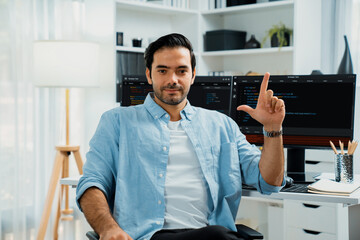 Profile's smart IT developer looking camera to pose against on software development coding on two pc screen, presenting program update online website on data company system at modern office. Surmise.