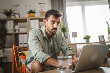 Wall Mural - Adult caucasian man sit and use laptop for work or fun at home