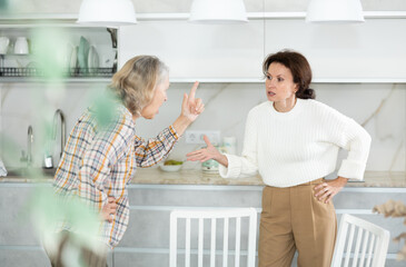 Wall Mural - Angry old and middle-aged women quarreling aggressively to each other standing at the kitchen table