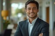 © Abdul Waris - portrait of Handsome smiling young successful businessman consultant looking at camera and smiling  with folded arms inside modern office. generated with ai