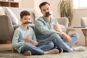 Canvas Print - Portrait of father and his little son with paper mustache at home