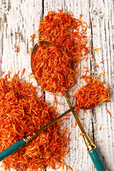 Wall Mural - Spoons with pile of saffron on white wooden background